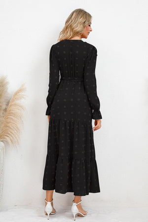 Back view of a woman wearing a Swiss Dot Tied Surplice Flounce Sleeve Dress, showcasing its elegant black design.