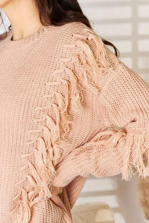 Close-up of And The Why tassel detail long sleeve sweater, showcasing bohemian fringe accents and soft pink texture.