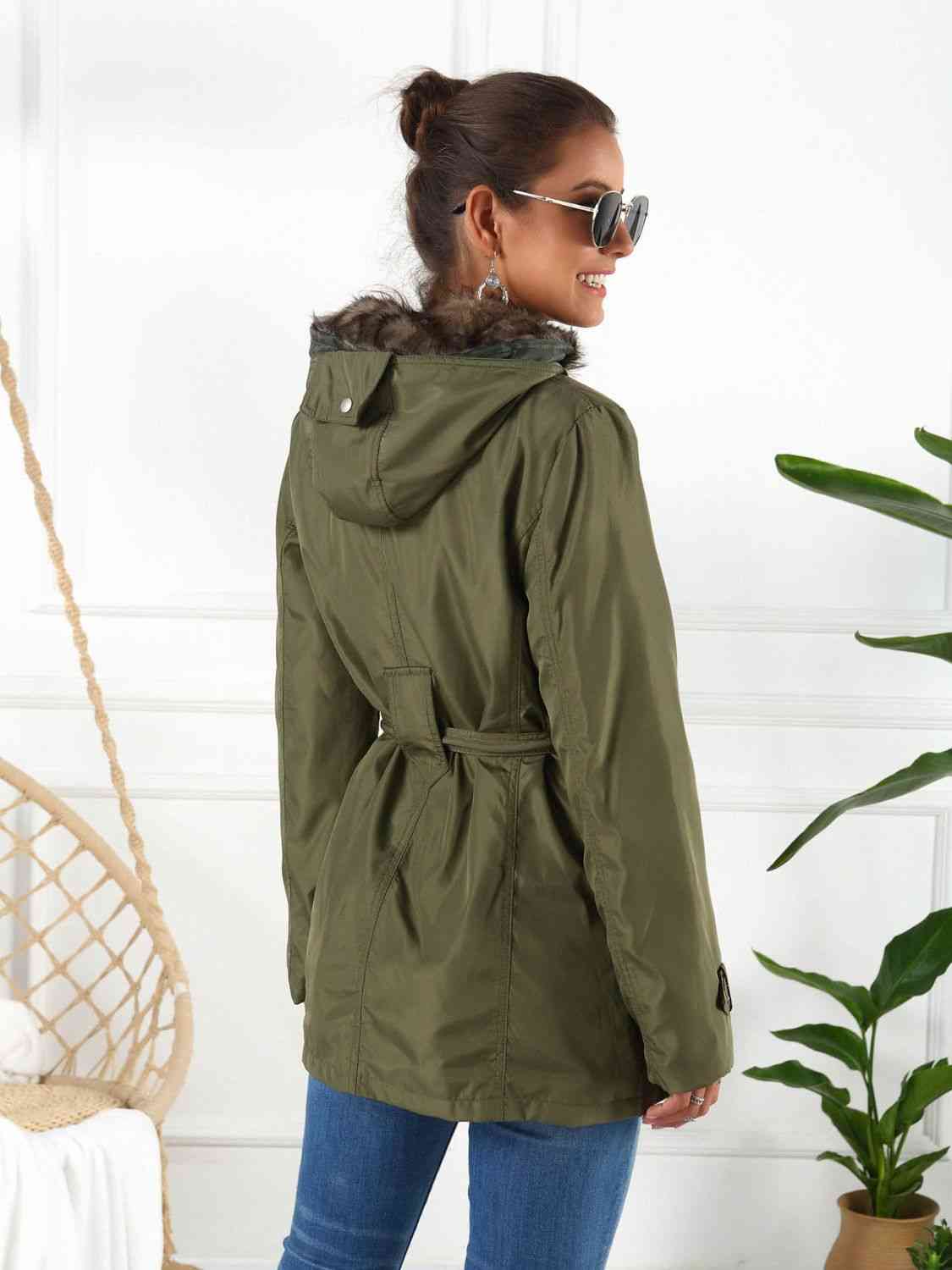 Woman in a full size hooded jacket with detachable liner, styling the jacket in olive green.
