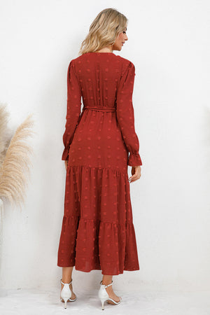 Back view of woman wearing Swiss Dot Tied Surplice Flounce Sleeve Dress in rust color, showcasing the tiered design.