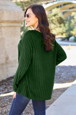 Woman in a green ribbed long sleeve top, showcasing the back style, paired with jeans and sunglasses at an outdoor location.