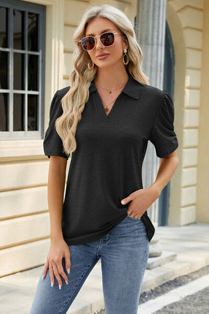 Stylish woman in a black eyelet collar puff sleeve blouse, paired with jeans and sunglasses, outdoors in a sunny setting.