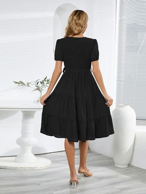 Smocked tie front short sleeve tiered dress in black, showcasing a stylish back view with a layered skirt.