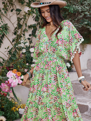 Smocked floral V-neck short sleeve dress in vibrant green with pink accents, styled with a cowboy hat and flowers.