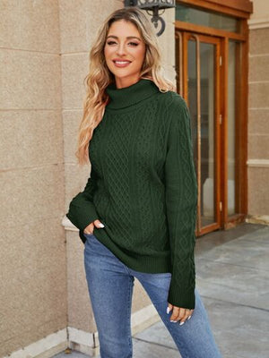 Woman wearing a green cable-knit mock neck sweater styled with blue jeans, posed outside a building.
