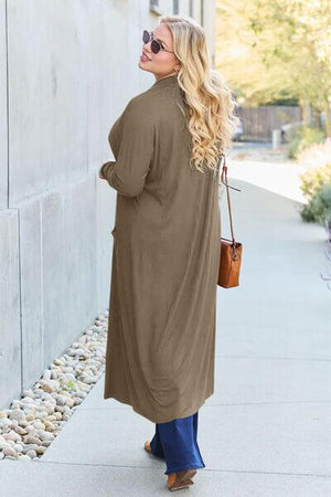 Model wearing Basic Bae open front long sleeve cover up in khaki, styled with jeans and sunglasses outdoors.