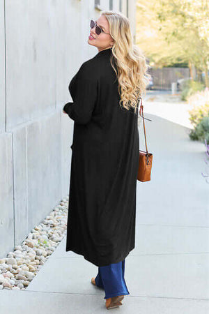 Woman wearing a black open front long sleeve cover up on a sunny street, showcasing its relaxed fit and stylish design.