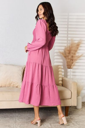 Woman in a pink ruffle trim smocked tiered dress, showcasing elegant movement and style.