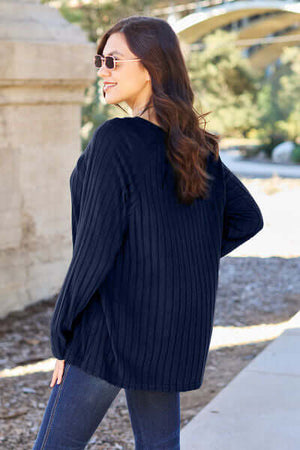 Woman wearing a navy ribbed long sleeve knit top outdoors, showcasing a relaxed fit and stylish sunglasses.