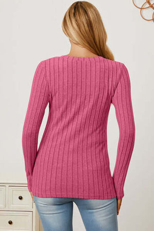 Back view of a woman wearing a pink ribbed long sleeve t-shirt, showcasing its fitted style and texture.