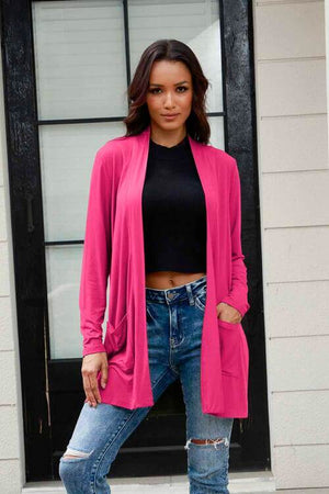 Model wearing Basic Bae pink long sleeve cardigan with pockets, paired with a black crop top and distressed jeans.