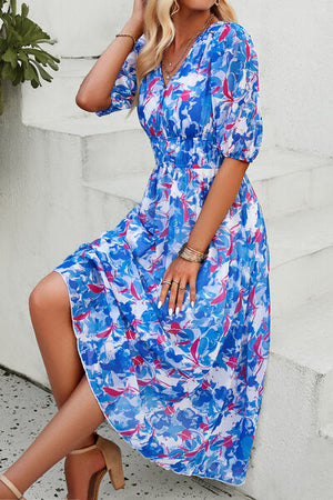 Model wearing a smocked printed V-neck short sleeve dress in blue and pink floral design, showcasing elegant summer style.