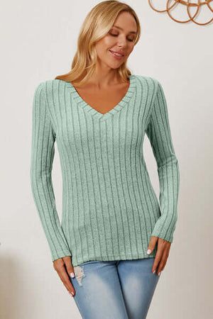 Model wearing a mint green ribbed V-neck long sleeve T-shirt, showcasing a basic style and slight stretch.