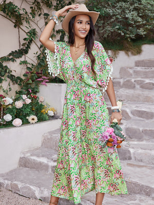 Smocked floral V-neck dress in vibrant green with short sleeves and lace trim, paired with a stylish hat and flowers.