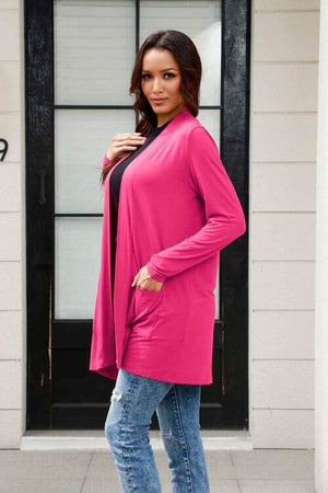Stylish woman wearing a pink long sleeve cardigan with pockets, paired with jeans, showcasing casual fashion.