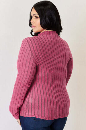 Back view of a plus-size model wearing a pink ribbed mock neck long sleeve t-shirt.