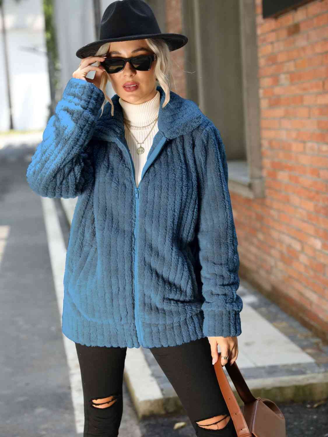 Model wearing a Zip-Up Collared Ribbed Jacket in blue, paired with a turtleneck and hat, showcasing a casual street style.