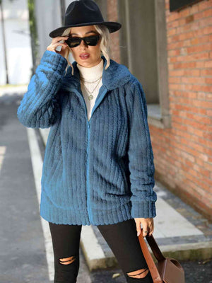 Model wearing a Zip-Up Collared Ribbed Jacket in blue, paired with a turtleneck and hat, showcasing a casual street style.