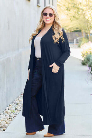Woman wearing Basic Bae open front long sleeve cover up with pockets, styled with jeans and sunglasses, outdoors.
