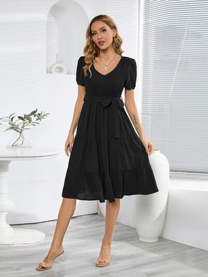 Smocked tie front short sleeve tiered black dress on model, perfect for casual summer outings.