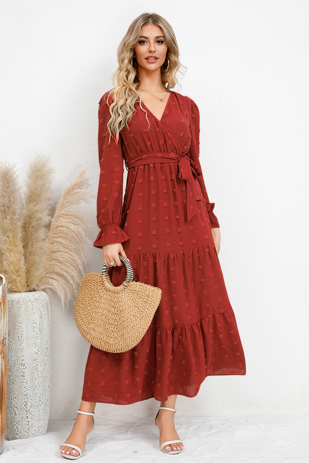 Model wearing a burgundy Swiss Dot Tied Surplice Flounce Sleeve Dress with a straw bag, showcasing feminine style.