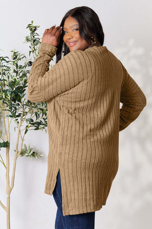 Plus size model showcasing a brown ribbed long sleeve top with a high-low slit, styled with blue jeans.