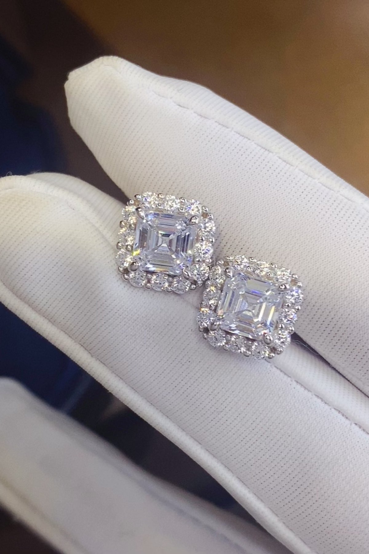 2 carat moissanite 925 sterling silver stud earrings displayed on a white jewelry holder with a matching box.