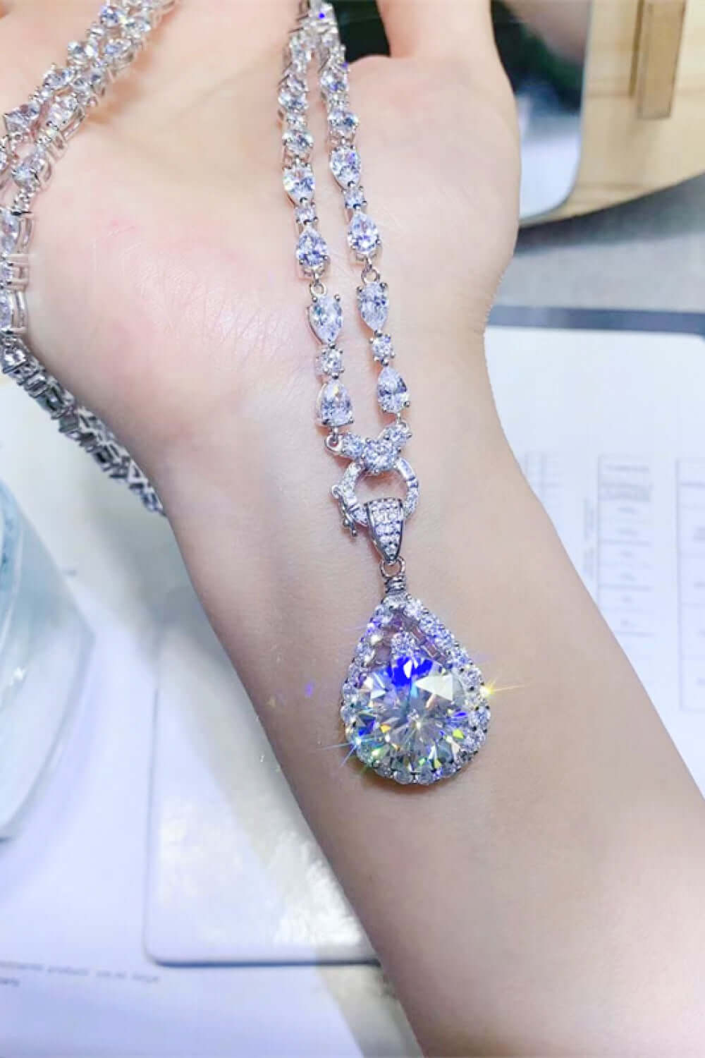 10 Carat Moissanite teardrop pendant necklace on hand, showcasing radiant sparkle and platinum-plated elegance.