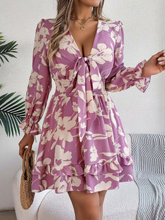 Tied ruffled long sleeve dress in floral print, featuring a flattering silhouette and soft pink hues.