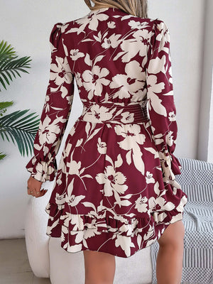 Back view of a burgundy ruffled printed long sleeve dress with floral design and tied waist.