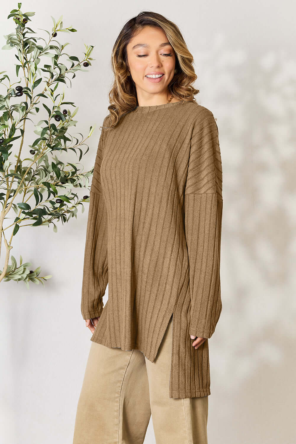 Model wearing Basic Bae ribbed long sleeve slit top in brown, styled with high-low hem and relaxed fit.