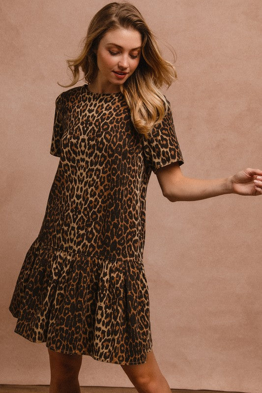 Woman modeling a leopard print tie back round neck short sleeve dress with ruffled hem.
