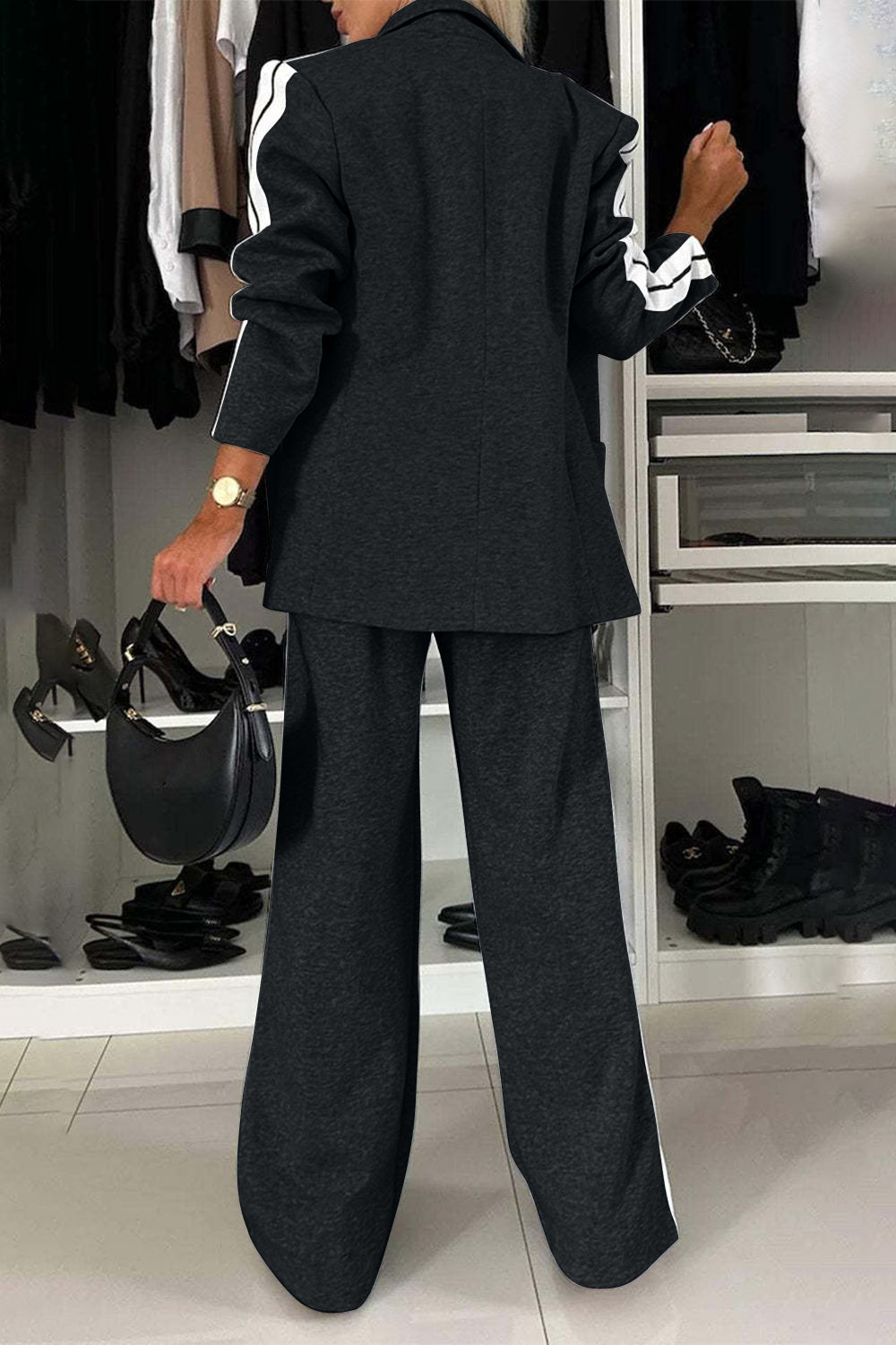 Back view of a woman in a full size black contrast lapel collar top and pants set, styled with a modern touch.