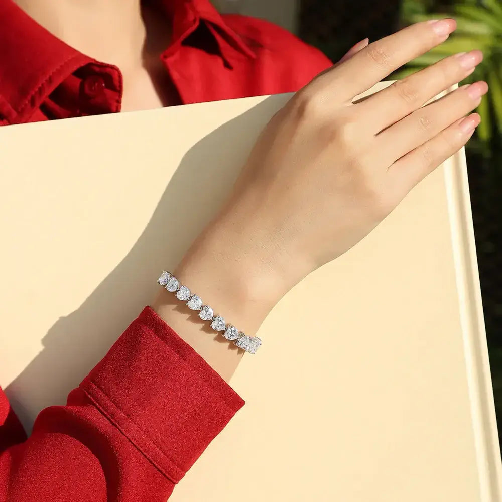 Woman wearing a 24 Carat Moissanite 925 Sterling Silver heart bracelet on her wrist.