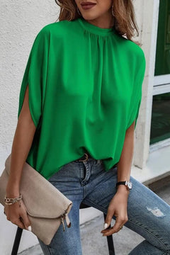 Woman wearing a green Tie Back Slit Half Sleeve Blouse with jeans and a clutch bag.