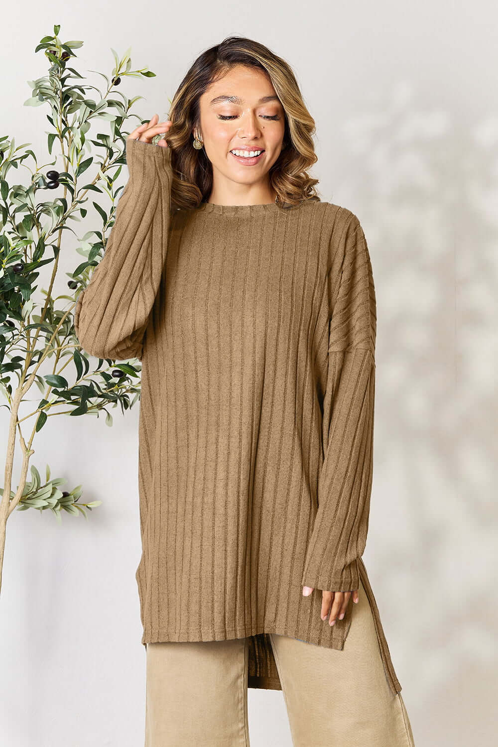 Woman in ribbed brown long sleeve top with side slit, styled casually in a natural setting.