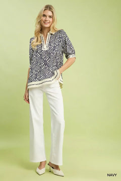 Umgee Geometric Leaf Print Popover Top styled with white pants against a green background.