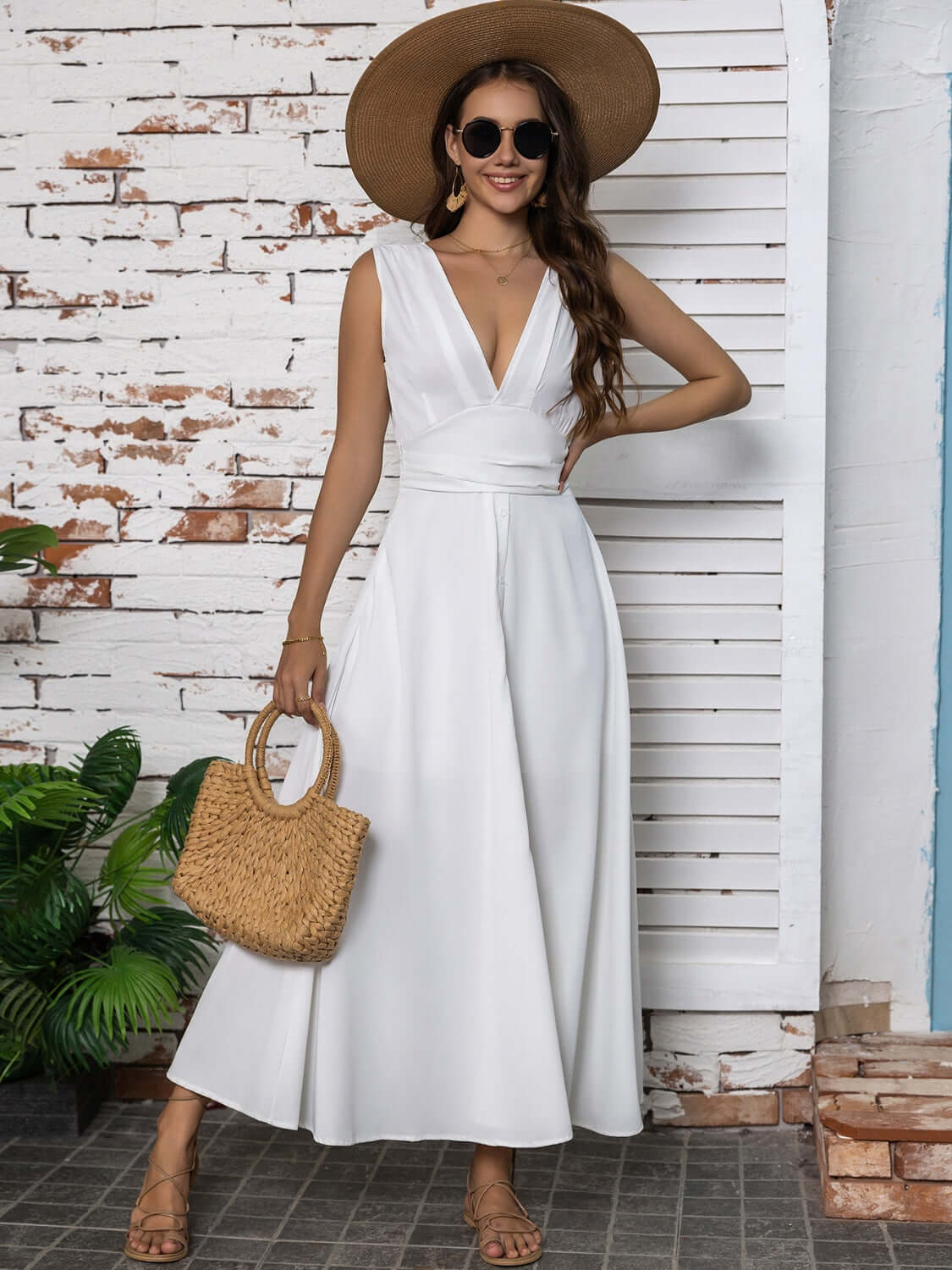 Full size slit v-neck sleeveless midi dress in white, styled with a large hat and woven bag, perfect for summer outings.