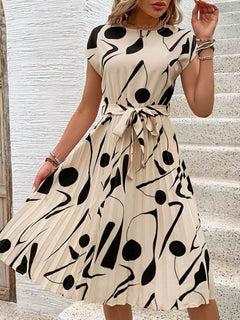 Tied pleated printed cap sleeve dress with bold black and cream pattern, perfect for casual or semi-formal occasions.
