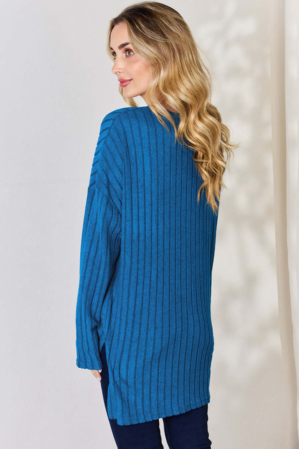 Model wearing a blue ribbed high-low T-shirt, showcasing back view with soft texture and relaxed fit.