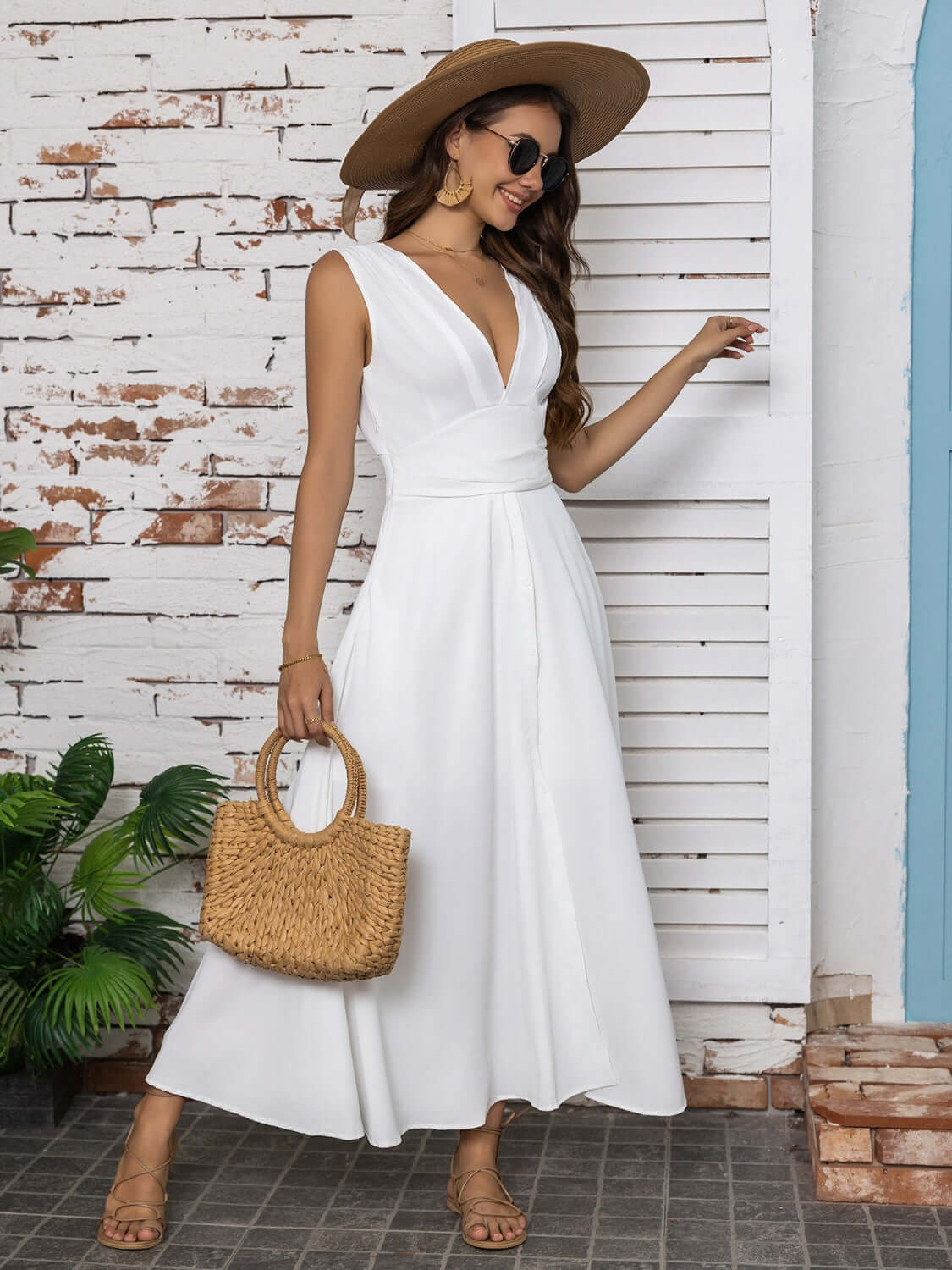 Full size slit V-neck sleeveless midi dress in white, worn with a straw hat and bag, styled with sunglasses.