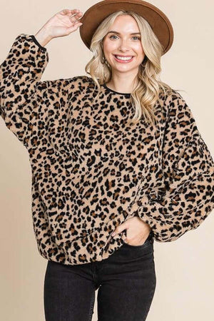 Woman wearing a leopard faux fur round neck top, showcasing its trendy style and cozy feel, paired with a brown hat.