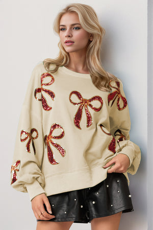 Model wearing a Double Take Sequin Bow Sweatshirt with red sequined bows, paired with a black skirt.