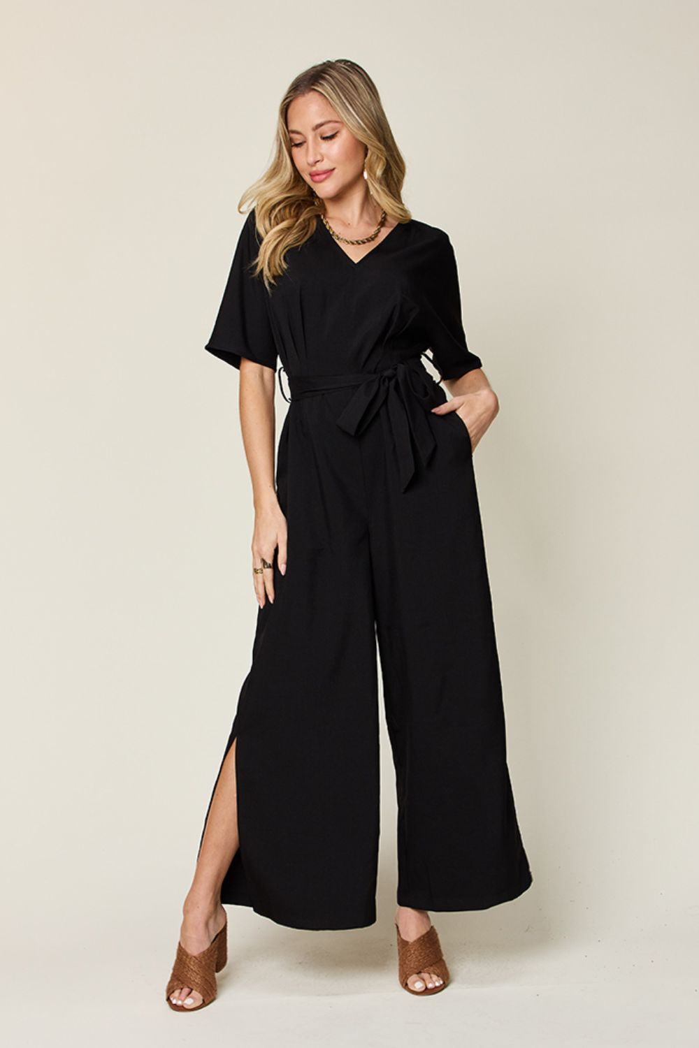 Double Take Full Size V-Neck Tie Front Short Sleeve Slit Jumpsuit - Elegant and versatile full-size jumpsuit featuring a flattering v-neckline, tie-front detail, short sleeves, and stylish leg slits. Perfect for any occasion, from casual outings to special events. Shop now for trendy fashion!"