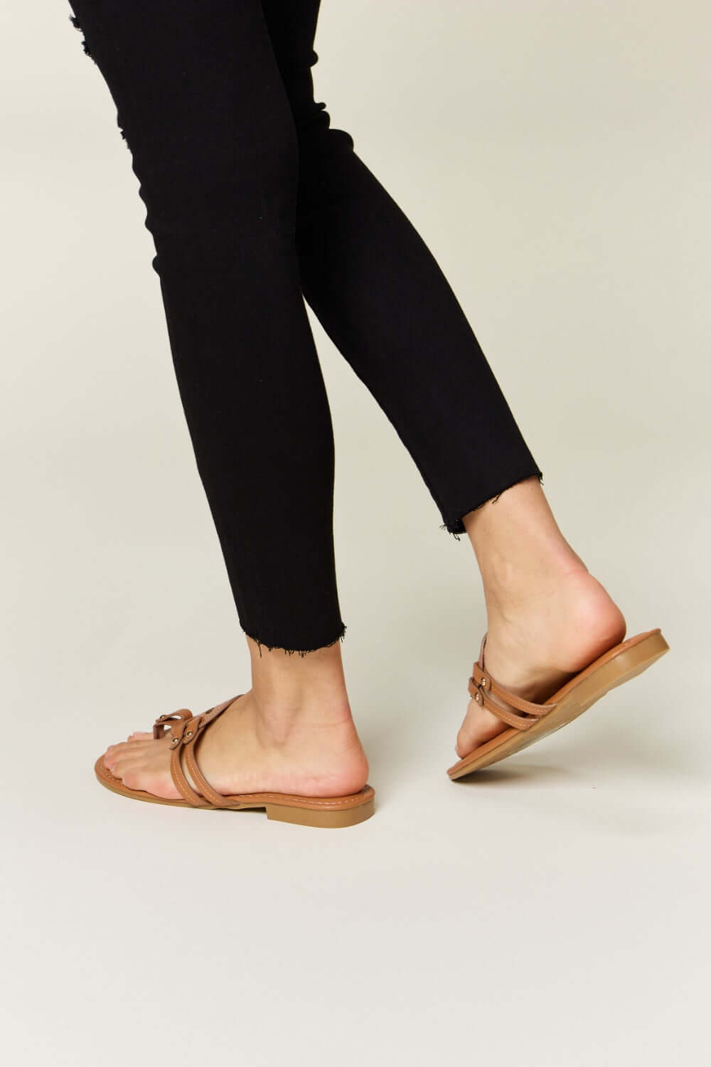 Woman wearing Forever Link Cutout PU Leather Open Toe Sandals with black jeans, showcasing stylish comfort.