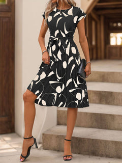 Model wearing a Tied Pleated Printed Cap Sleeve Dress with a black and white design, perfect for stylish casual outings.