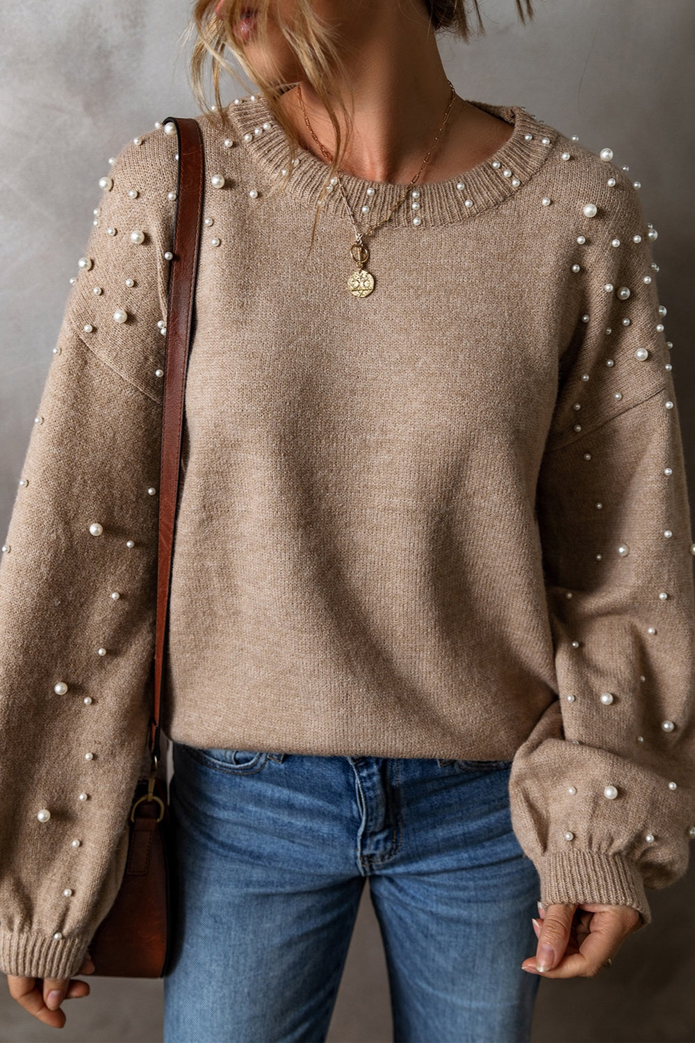 Women's pearl detail round neck long sleeve sweater in beige, styled with jeans and accessories, perfect for casual elegance.