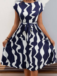 Tied pleated cap sleeve dress in navy and white wavy print, showcasing a flattering silhouette and stylish design.