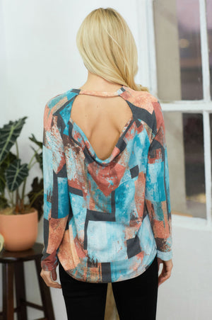 Model wearing an artistic open-back long sleeve top with colorful abstract patterns.