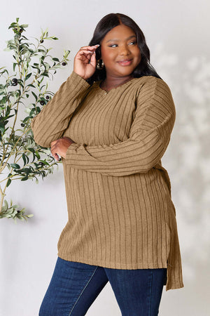 Curvy model wearing a ribbed, long sleeve, high-low slit top in brown, showcasing a relaxed fit and stylish design.